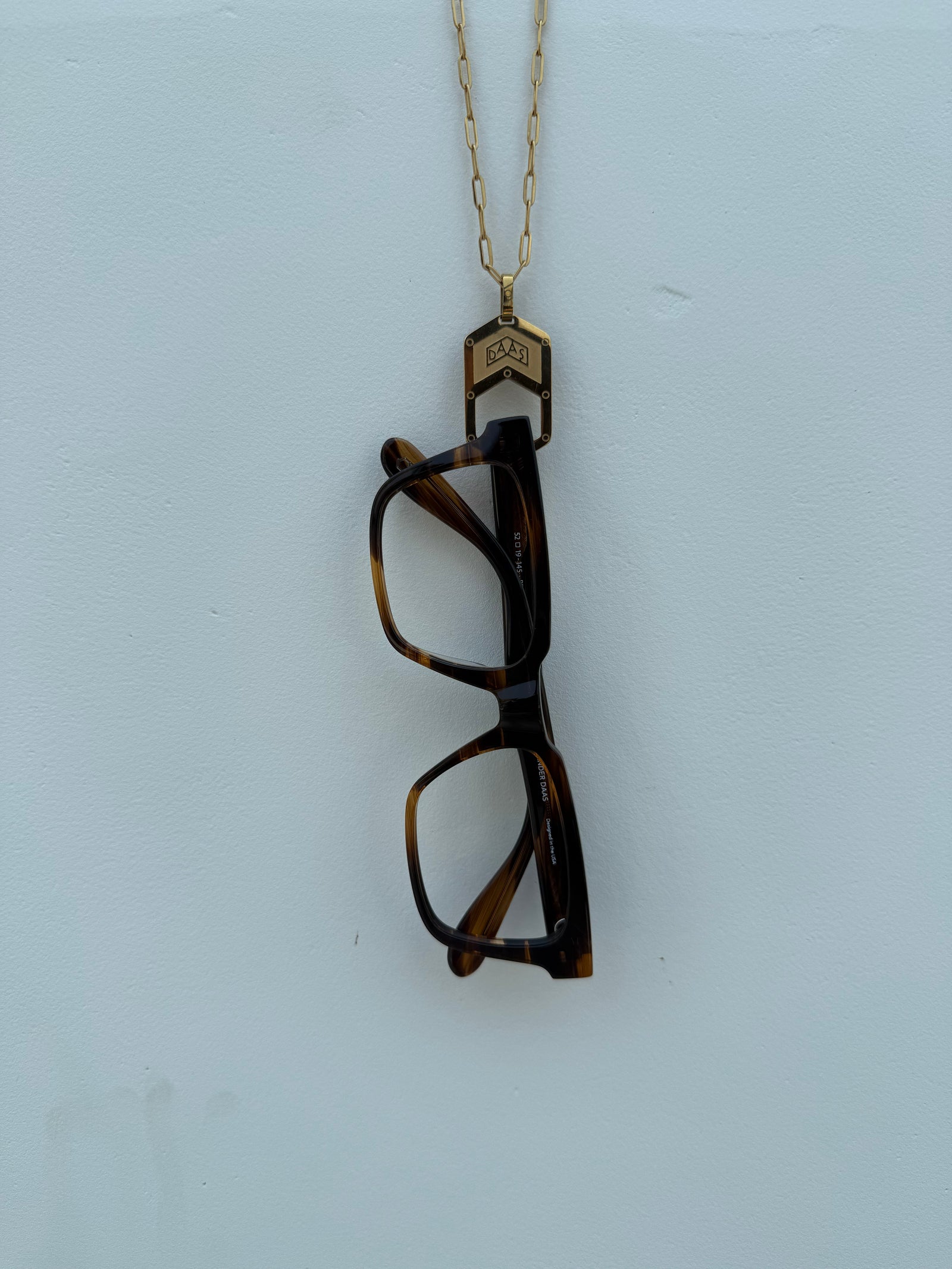 The Palma Glasses Chain with Alexander Daas frame hanging on it.