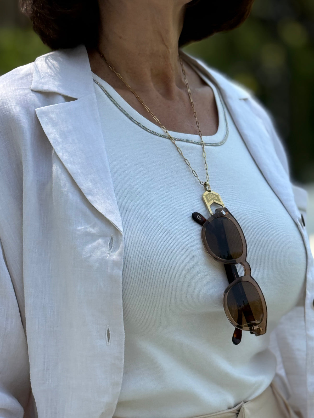 Woman wearing The Palma Glasses Chain Gold with Alexander Daas sunglasses hanging from it.