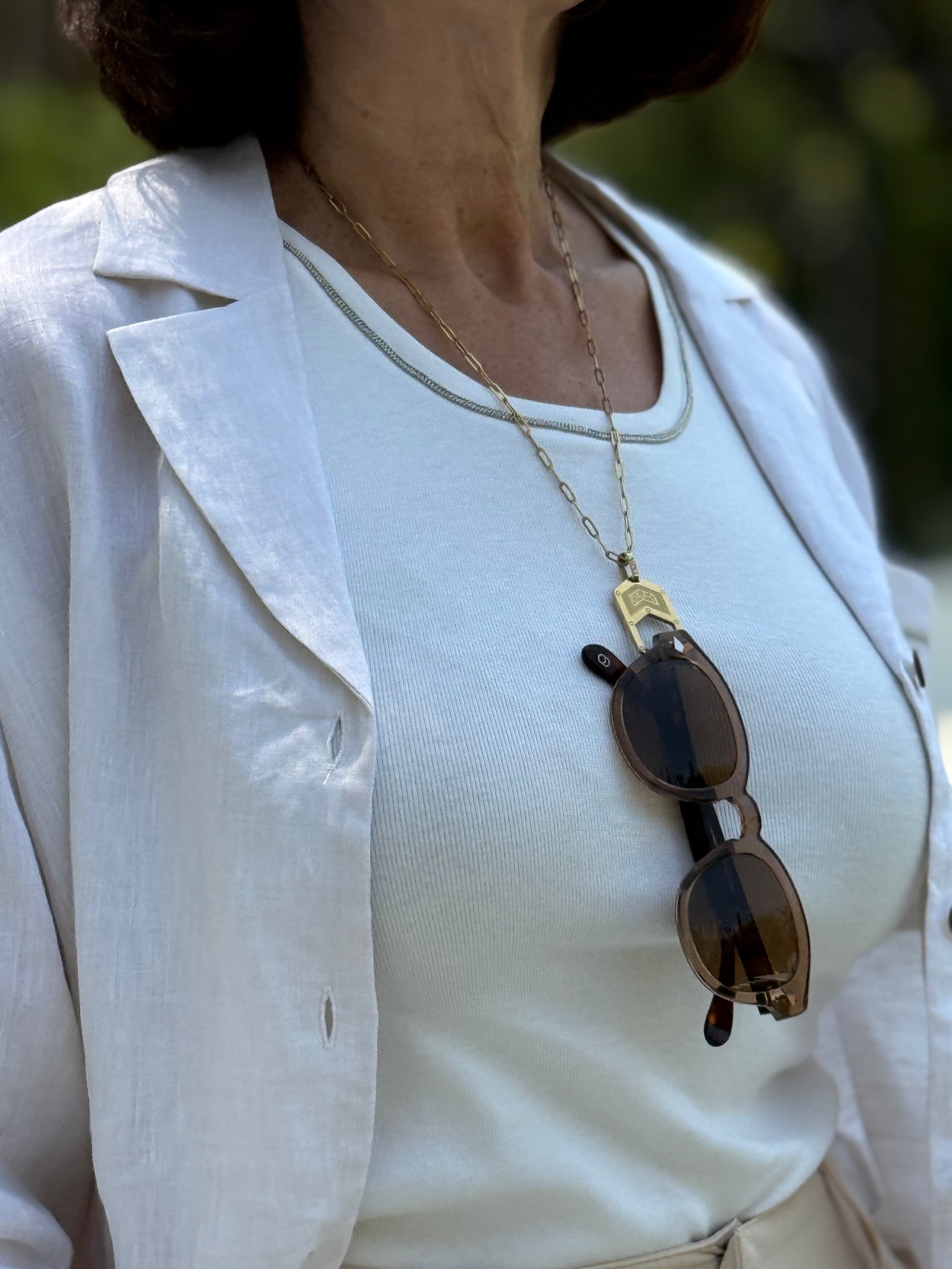 Woman wearing The Palma Glasses Chain Gold with Alexander Daas sunglasses hanging from it.