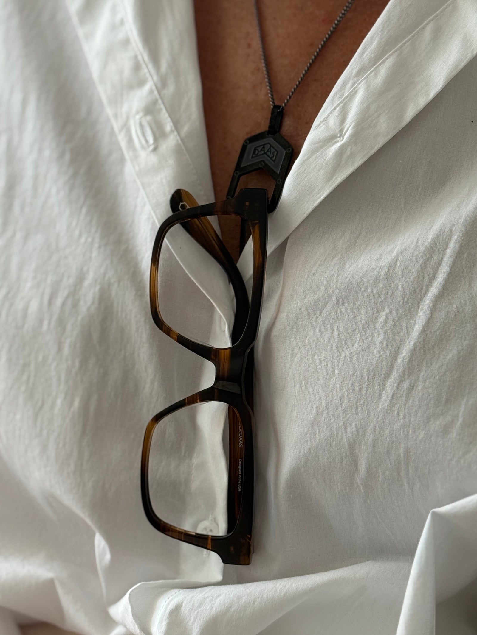 The Roma Glasses Chain with Alexander Daas glasses hanging on it.